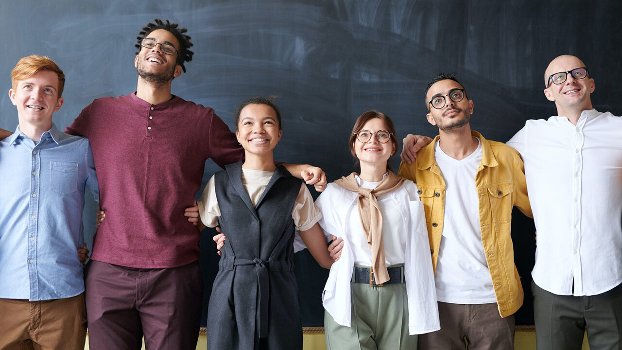 Photo of six men and women standing in front of a chalkboard