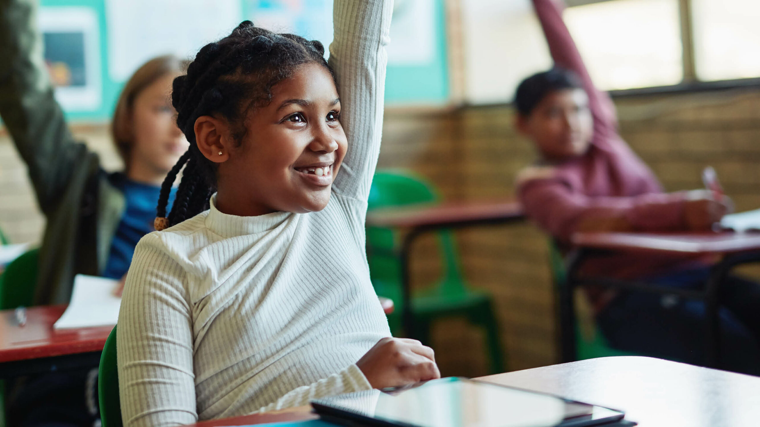 Young children in a classroom raising their hands to answer a question
