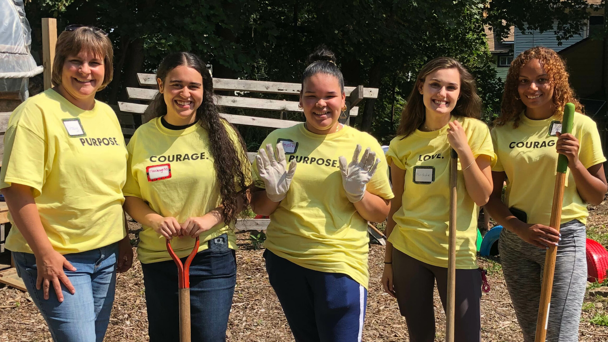 Photo of five women volunteers with shovels and rakes at a worksite.
